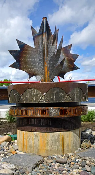 A large carved and painted drum standing upright outdoors