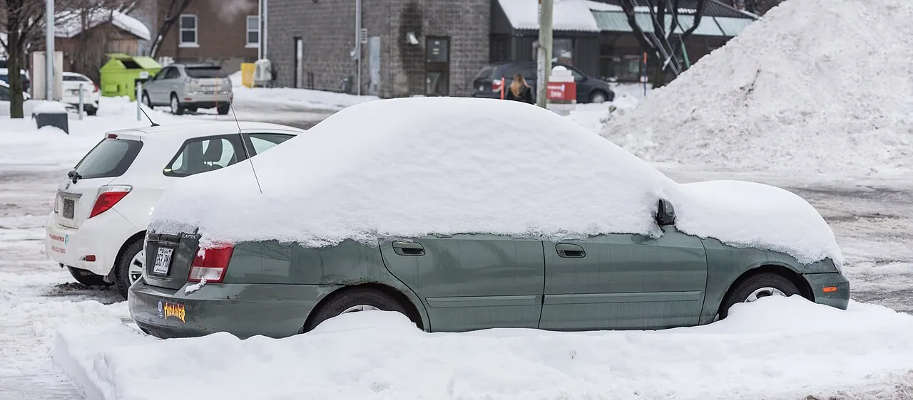 A car buried under heavy snow on a residential street