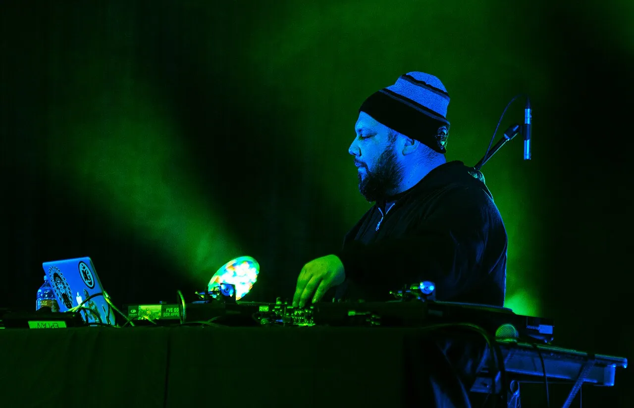 A DJ performing under green stage lights at the Civic Centre during Coldsnap