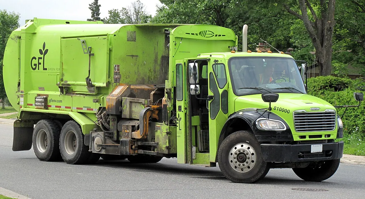 A green side-loading recycling truck parked on a residential street