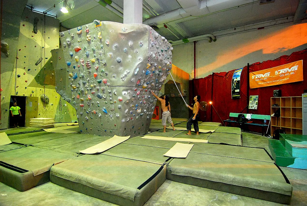 An indoor bouldering wall above thick crash mats