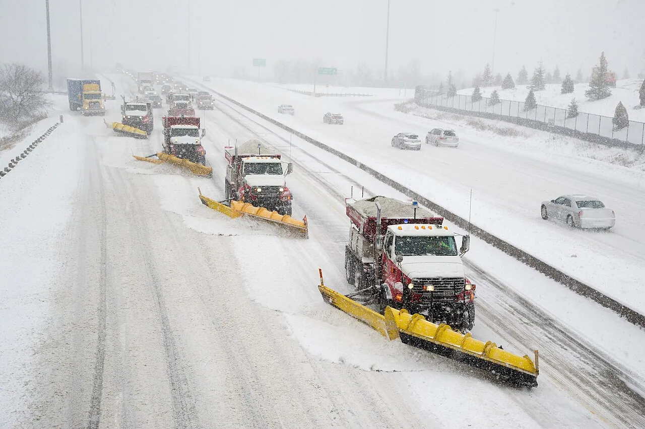 A line of snowploughs clearing a wide road during a snowstorm (Toronto, shown as a generic example)