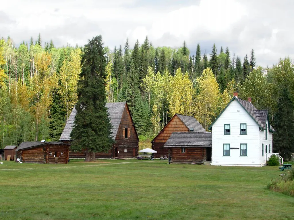 Log and white wooden buildings at the Huble Homestead Historic Site among tall trees