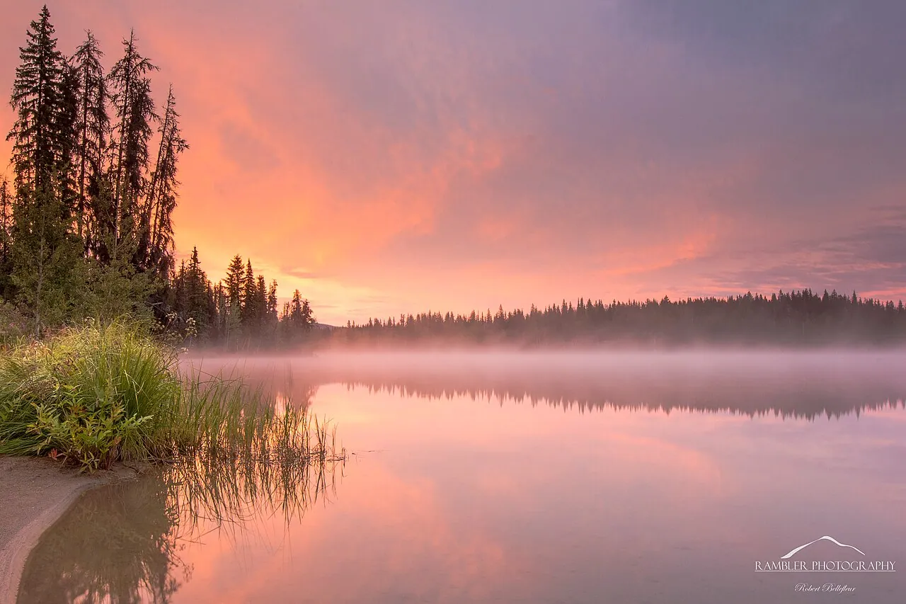 A pink sunrise reflected in calm water at Crooked River Provincial Park