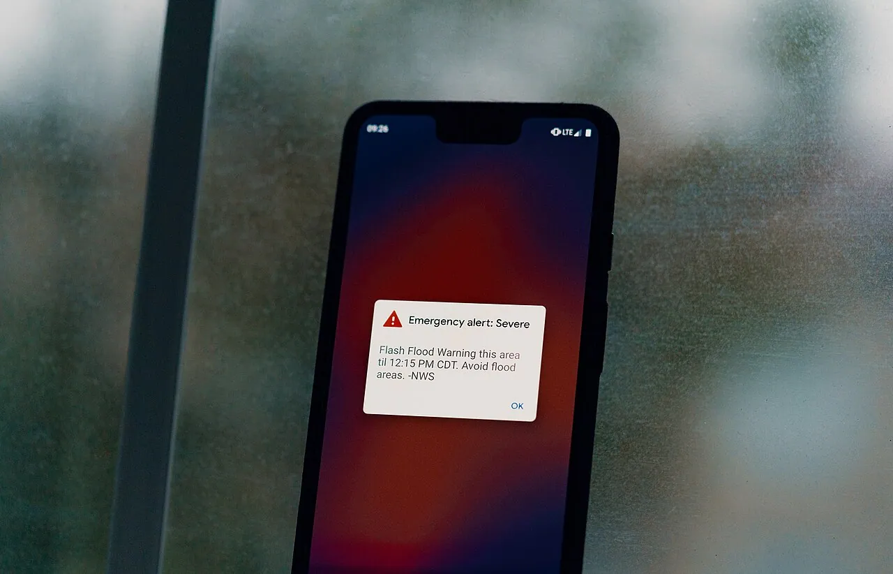 A smartphone lock screen showing a wireless emergency alert warning of a flash flood