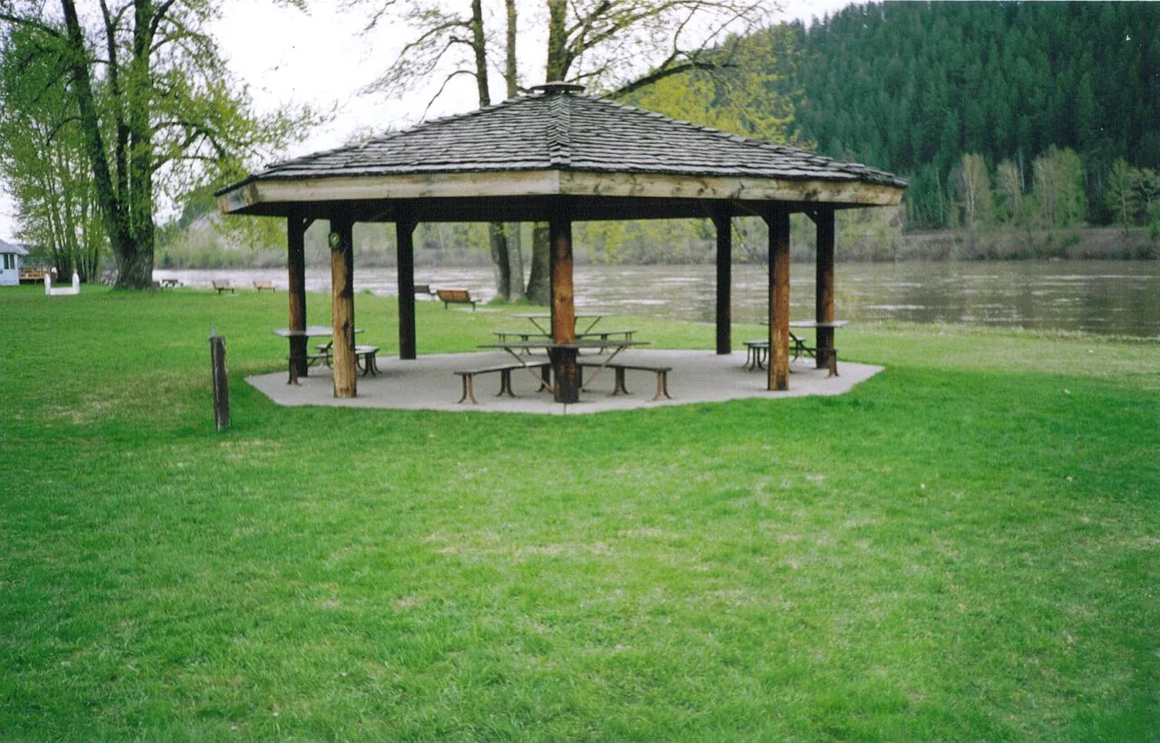 A wooden picnic gazebo on the lawn at Paddlewheel Park beside the Nechako River in Prince George